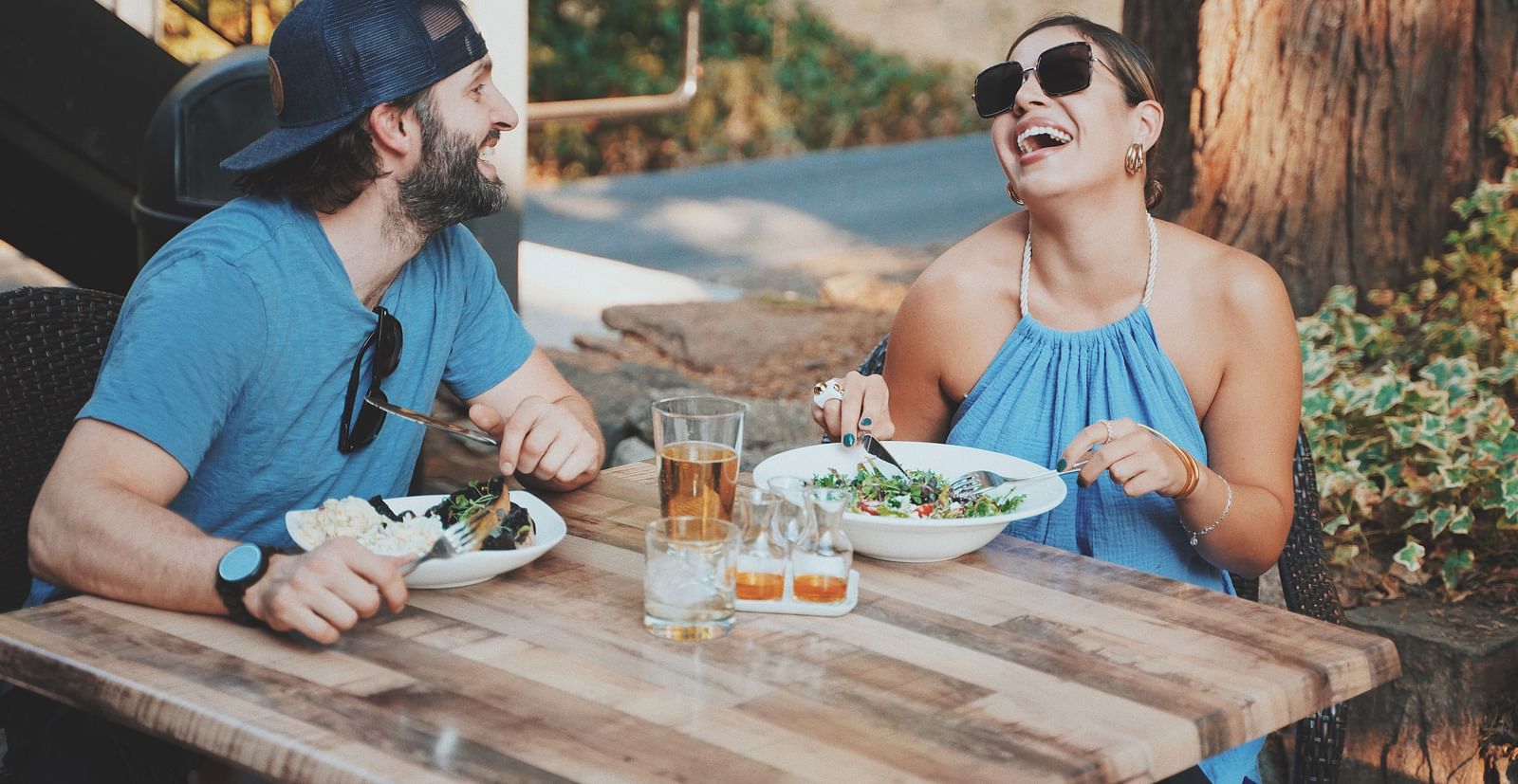 A couple laughing at a table under the sun - The Groveland Hotel.