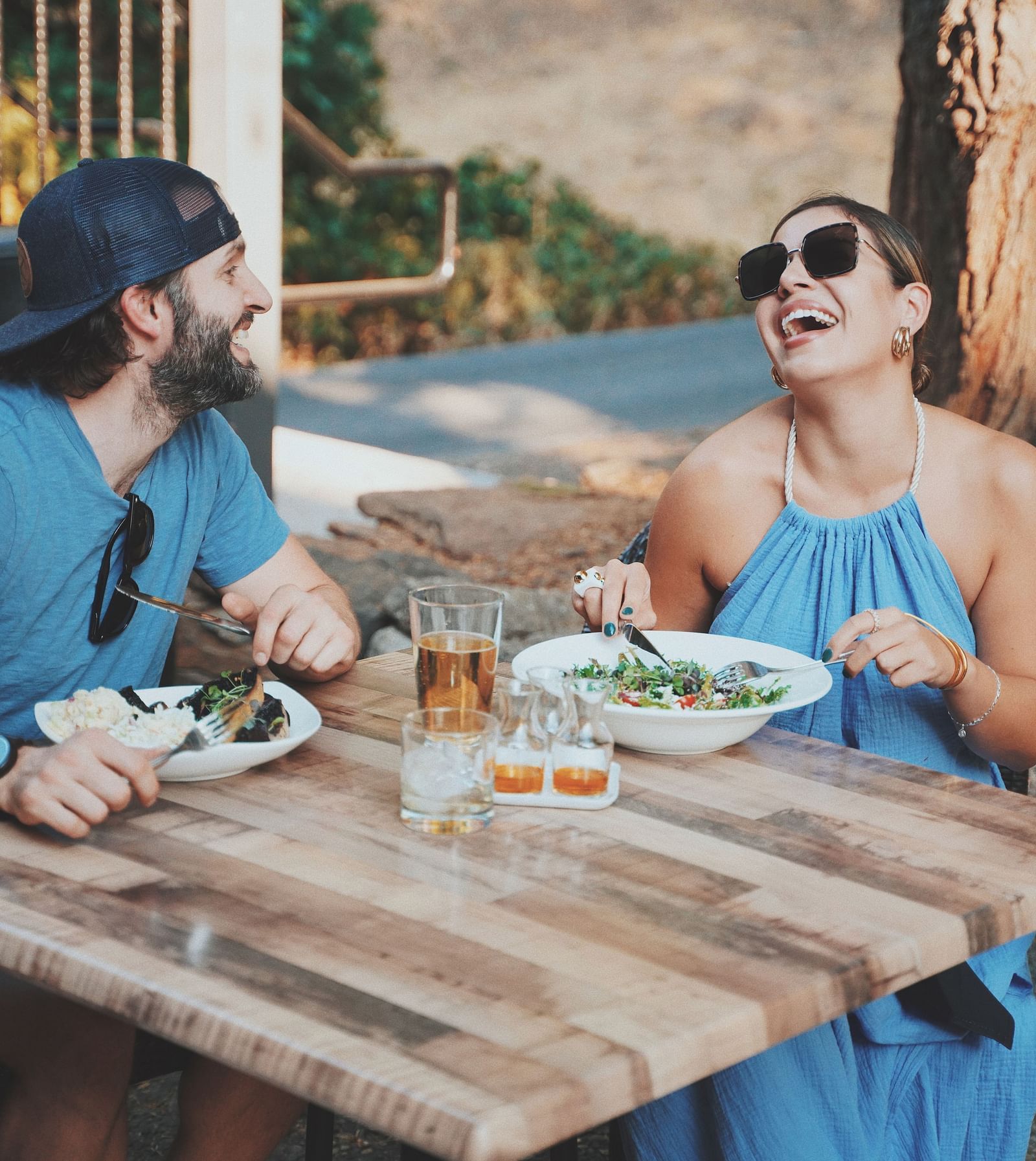 A couple laughing at a table under the sun - The Groveland Hotel.
