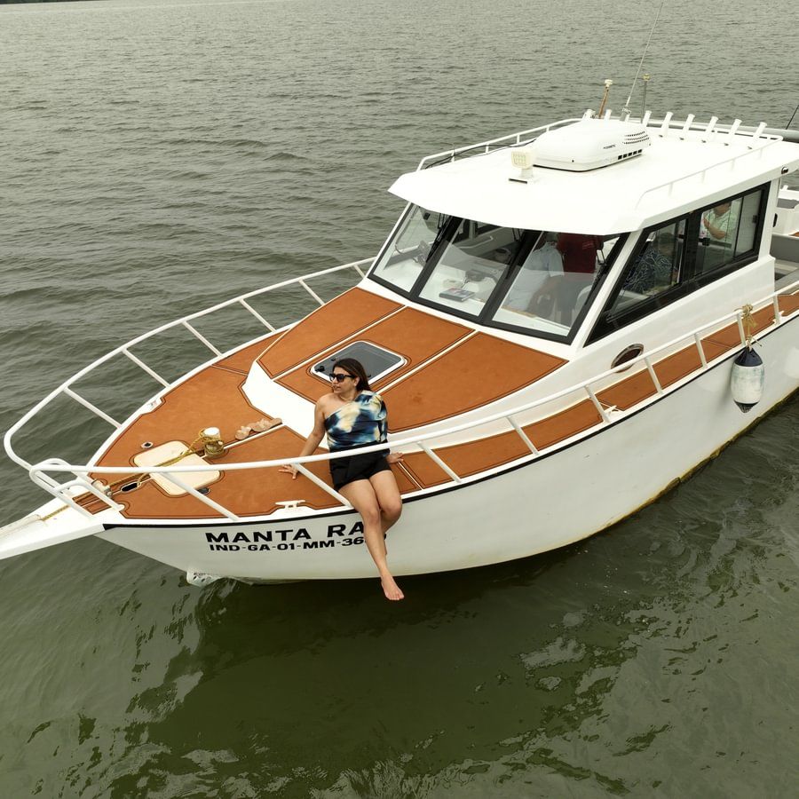 A low-angle shot of a white and brown motorboat with a woman sitting in the front cabin, moored on a murky body of water.