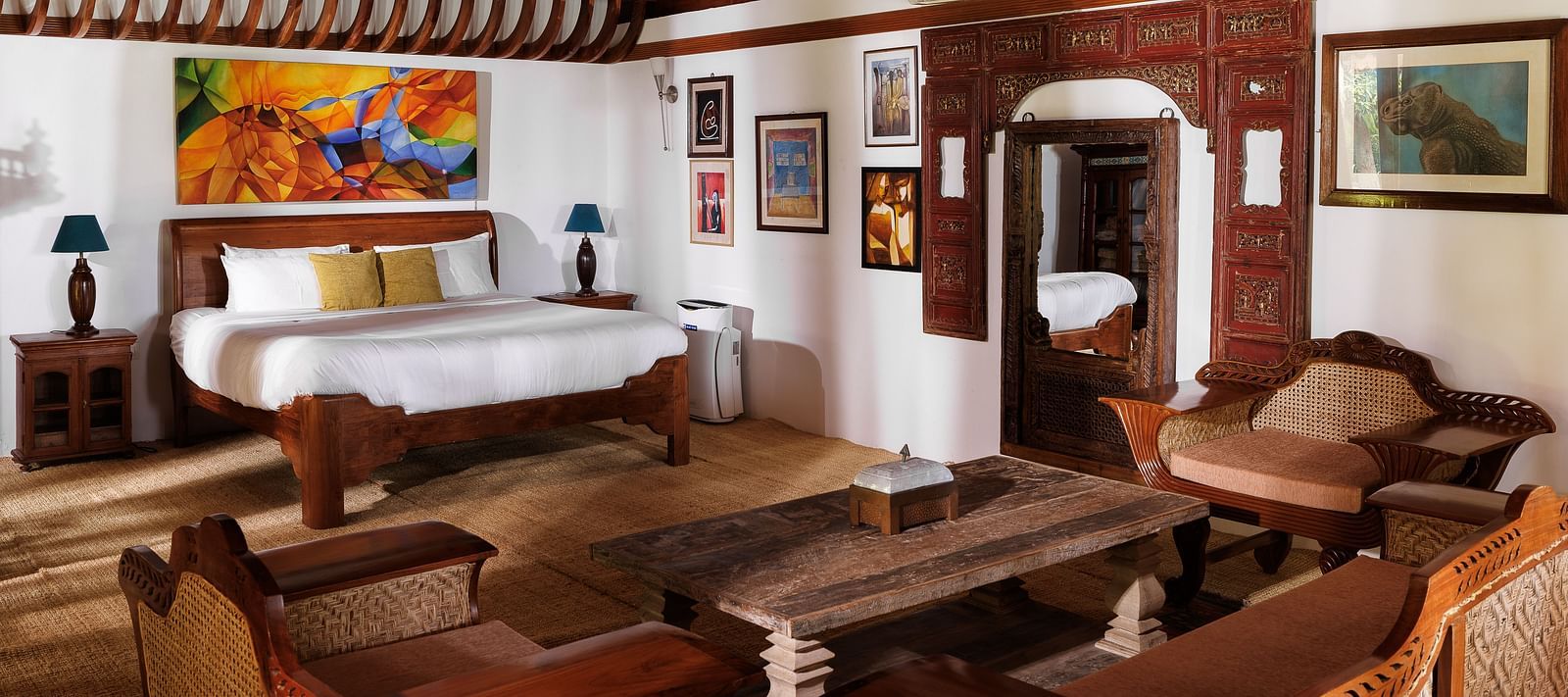 A wooden interior room with wooden furnitures such as a bed, a sofa set, a coffee table, and paintings - BluSalzz Villas - Muhamma Resort, Alleppey