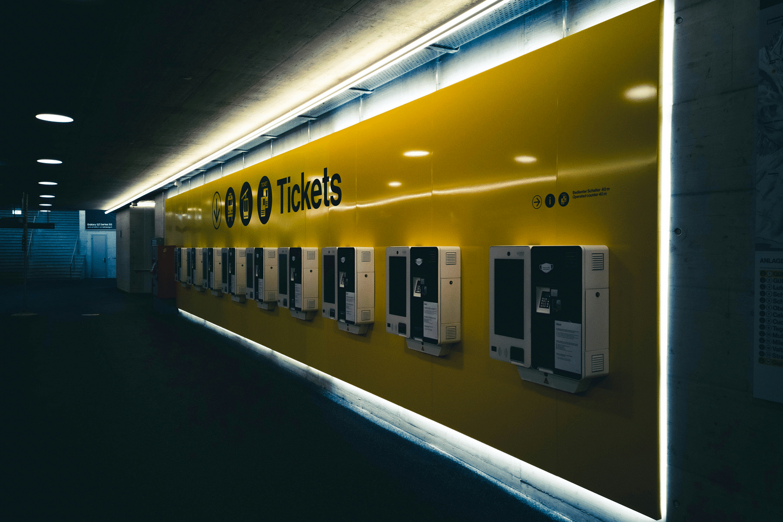a ticket counter with led lights on in the night with yellow coloured exterior