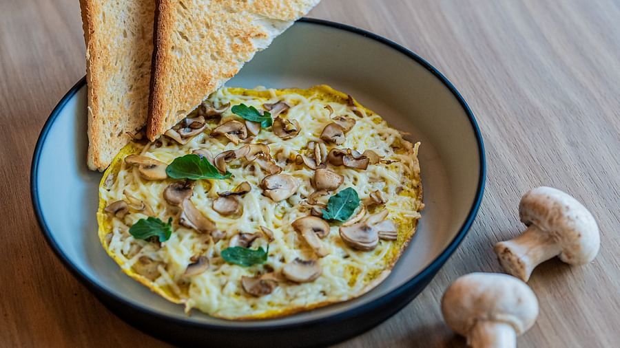 A deep plate with mushroom omelette, basil leaves, toast on the side, and mushrooms beside the plate at Indie Stays Mumbai International Airport.