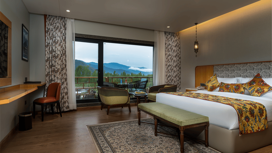 Spacious guest room at Mountnoor Sarovar Premiere, Pahalgam with modern décor and scenic outdoor views.