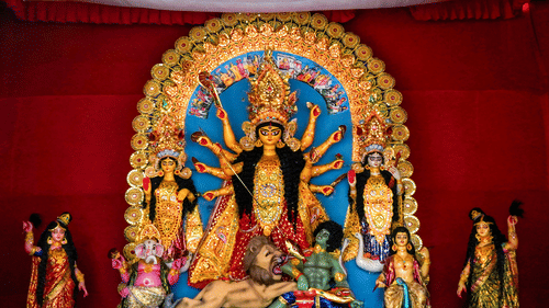 A large and vibrant Durga Puja idol, showing the goddess Durga with ten arms slaying a demon. She is surrounded by her children: Lakshmi, Saraswati, Ganesha, and Kartikeya.
