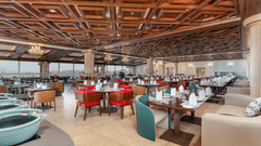 An image of our restaurant in Srinagar with high ceilings made of wooden ascents and spacious dining arrangement - Sarovar Premiere, Srinagar 