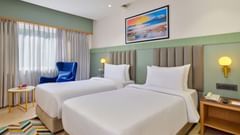 An image of a room featuring twin beds with a decorative photo frame displayed above them at  Tulip Inn, Bhopal.