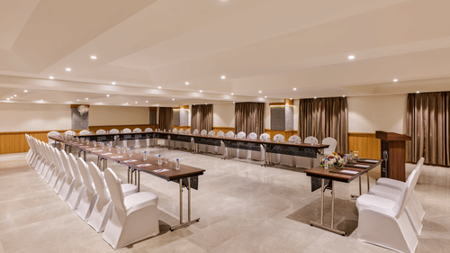An image of a banquet hall at Tulip Inn, Bhopal, featuring a U-shaped seating arrangement.