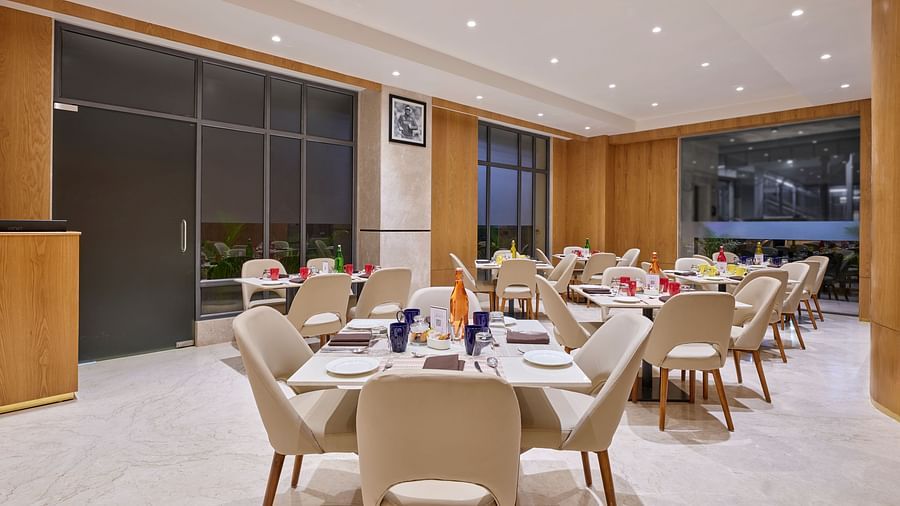 Hotel dining space with large windows, offering a view while guests enjoy their meals - Biznotel by Pride Motera, Ahmedabad
