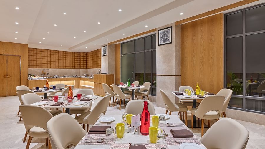 Hotel dining area with beautifully set tables and chairs, waiting for diners - Biznotel by Pride Motera, Ahmedabad