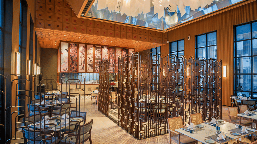 Wide view of CHINCHIN restaurant at The Residency Signature Madurai with dining tables, decorative partitions, and a statement chandelier.