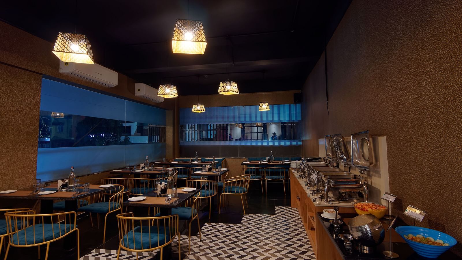 Interior of M Cafe with chairs and tables and lights hanging from the ceiling at Ankit Hotel, Jabalpur