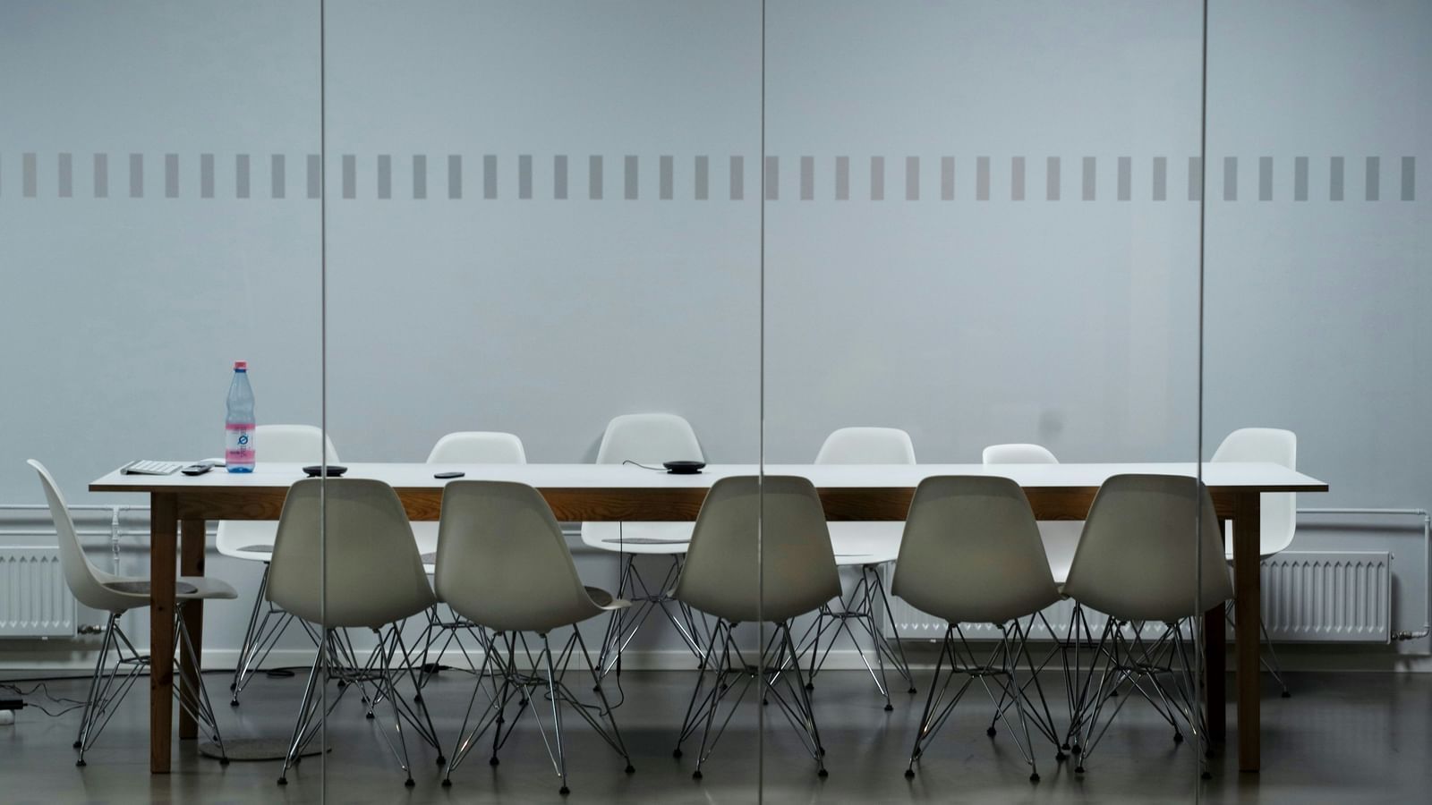  A modern conference room with a long table, white and grey chairs, and a glass partition