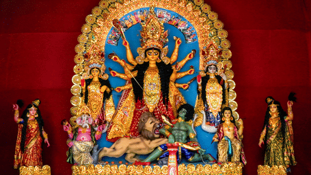 A large and vibrant Durga Puja idol, showing the goddess Durga with ten arms slaying a demon. She is surrounded by her children: Lakshmi, Saraswati, Ganesha, and Kartikeya.