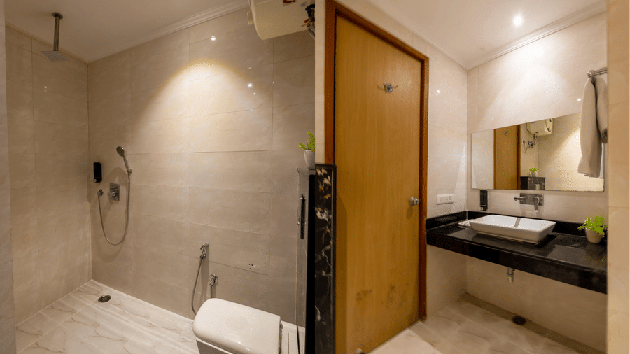 Bathroom features contemporary tiling, a modern sink basin on a dark vanity, and a glass-enclosed shower area with rainfall and handheld shower fixtures at Hotel Corporate Suites