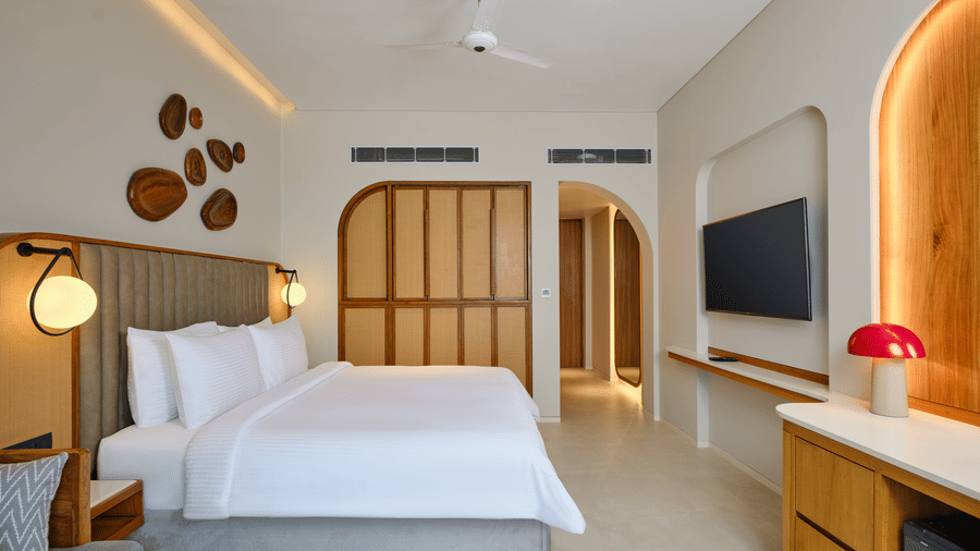 The Premium Room at Swosti Premium Beach Resorts, Puri, featuring a double bed, a television mounted on the wall, and modern wooden decor. 