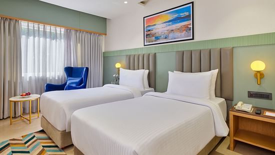 An image of a room featuring twin beds with a decorative photo frame displayed above them at  Tulip Inn, Bhopal.