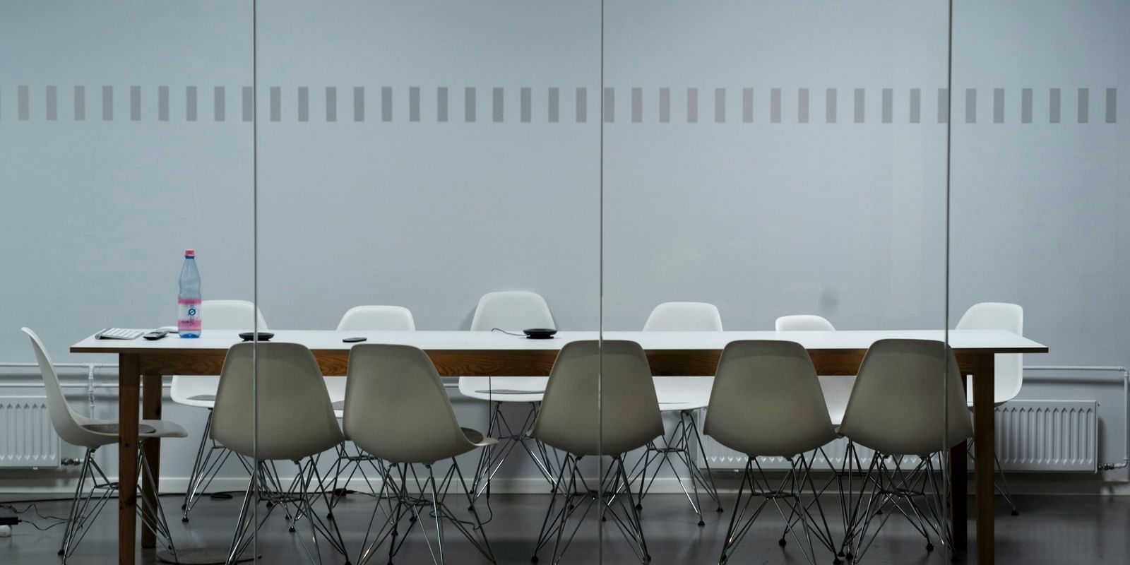  A modern conference room with a long table, white and grey chairs, and a glass partition