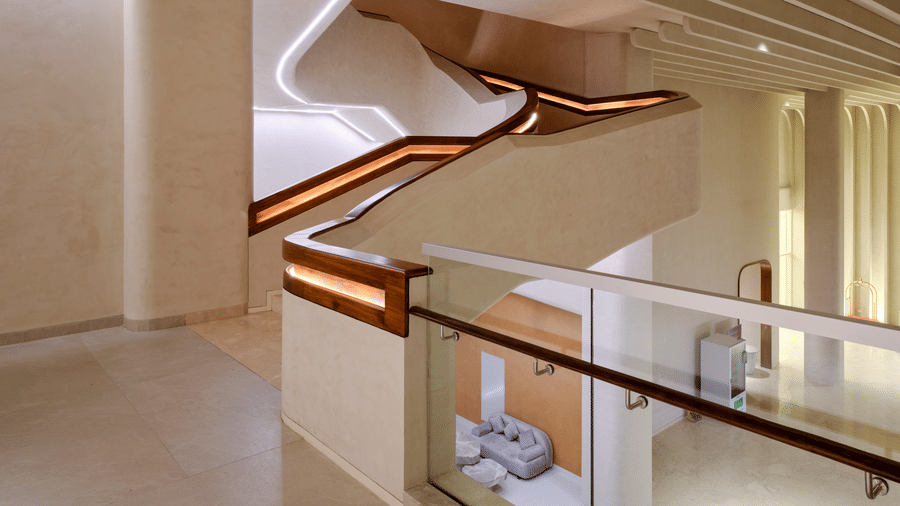 Café Hanging staircase at Swosti Premium Beach Resorts, Puri, featuring a flowing, curved staircase with glass railings and integrated lighting.