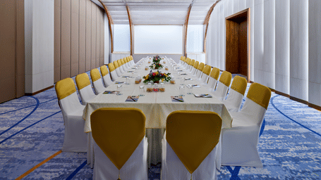The Mahari Courtyard hall at Swosti Premium Beach Resorts, Puri, with a tablecloth and chairs in a modern venue with a distinctive curved ceiling structure.