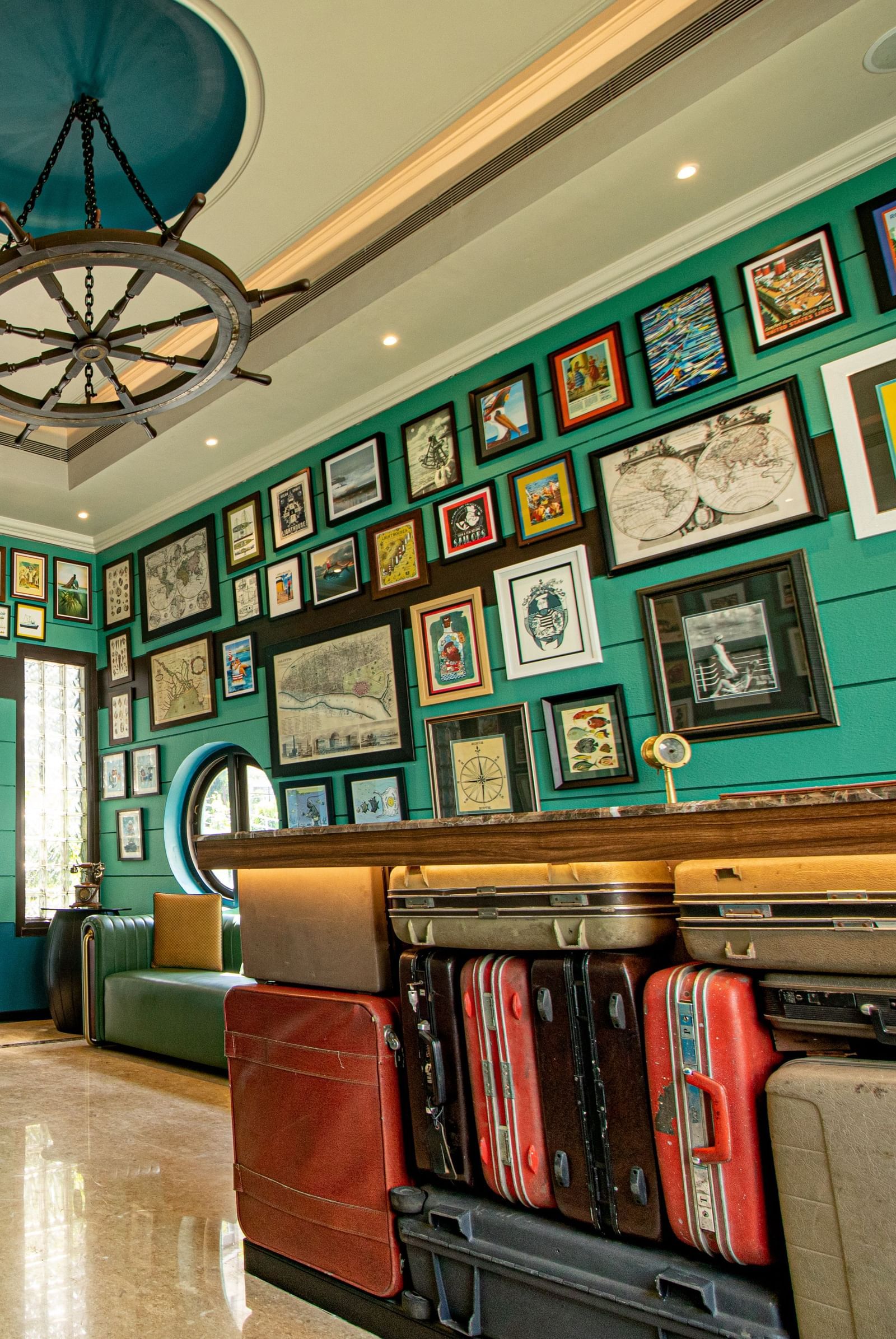 An indoor-outdoor seating area at Polo Floatel Kolkata with a view of the river. The room has a red and grey tiled floor and is furnished with a comfortable red chair and sofa. 