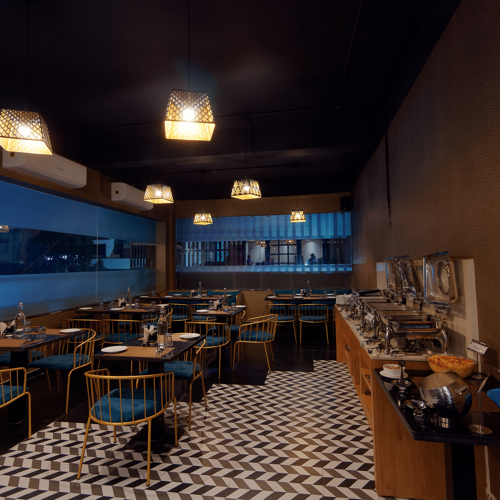 Interior of M Cafe with chairs and tables and lights hanging from the ceiling at Ankit Hotel, Jabalpur