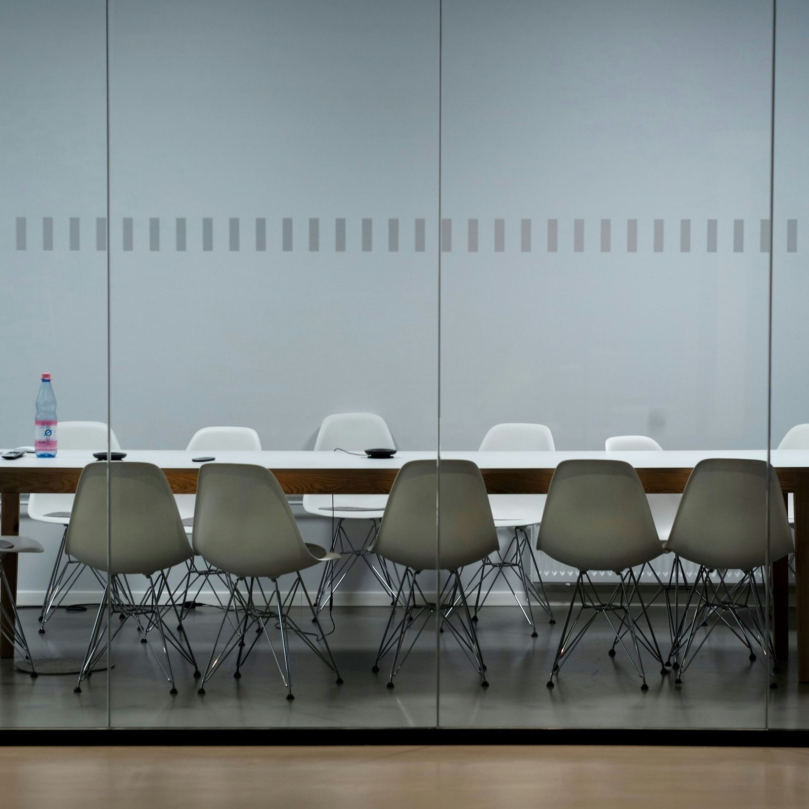  A modern conference room with a long table, white and grey chairs, and a glass partition