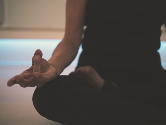 A person practising meditation with a hand in a mudra gesture.