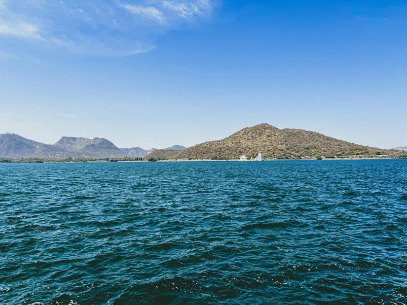 Turquoise water of Fateh Sagar Lake in Udaipur on a sunny day with a backdrop of Aravalli Hills