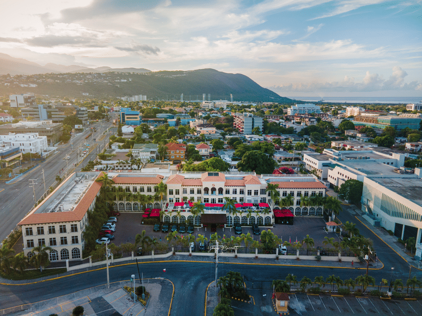 Facade of S Hotel Kingston with a red-roofed central area, surrounded by a city and mountains