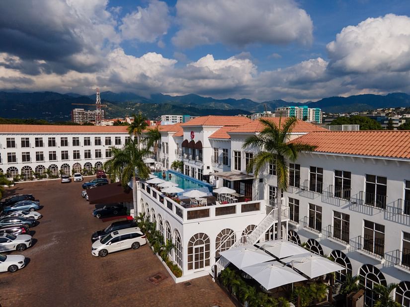 An aerial image of our hotel in Kingston, embraced by lush green palm trees and a spacious parking area - S Hotel Kingston, Jamaica