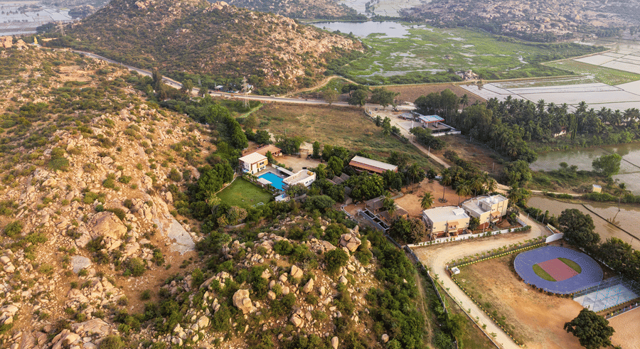 Wide aerial shot of the resort property and the rugged rocky landscape of Hampi in the distance - Nature Trails Ashoka Resort Hampi