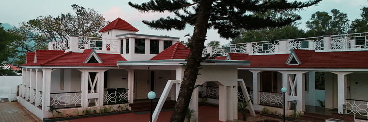 Facade view of MGM Whispering Nest, Yelagiri with a tree near the entrance.