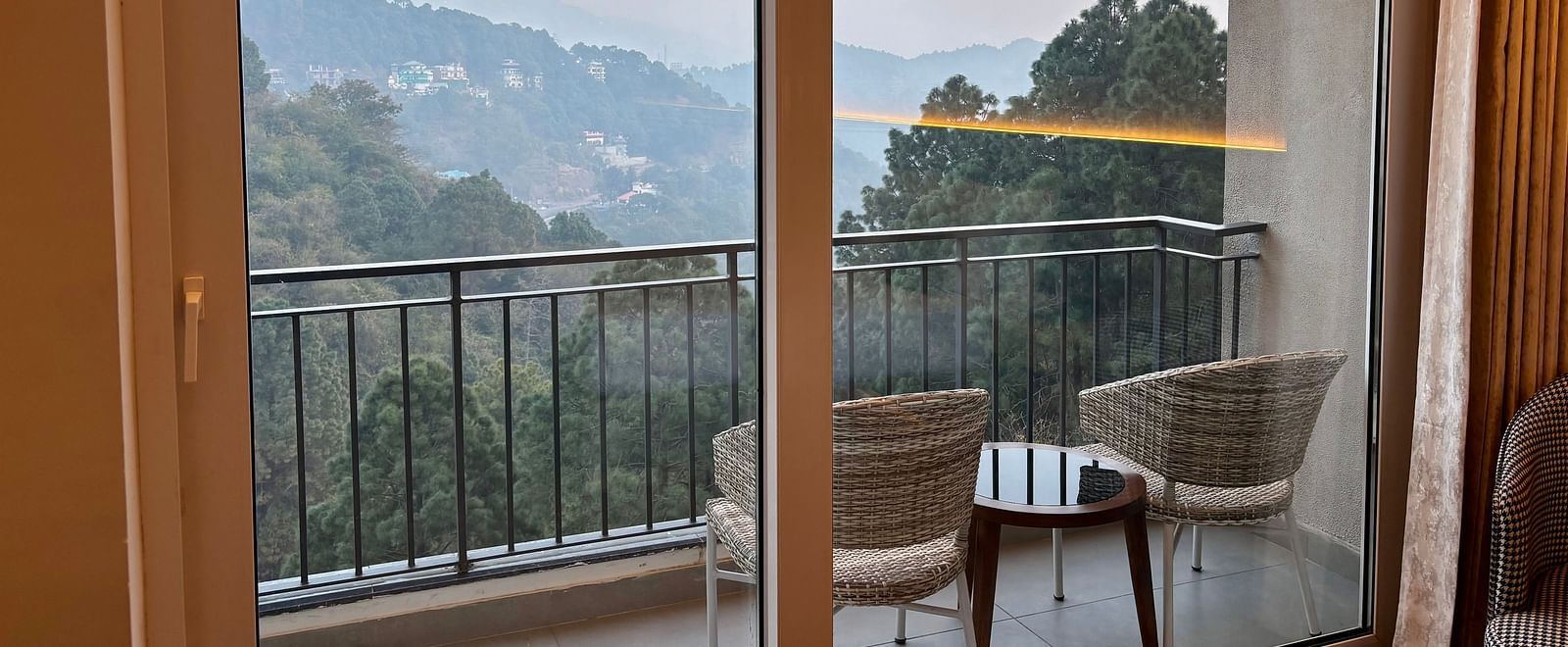 Balcony view with chairs and a table overlooking scenic hills and greenery at ARNISA Boutique Hotel