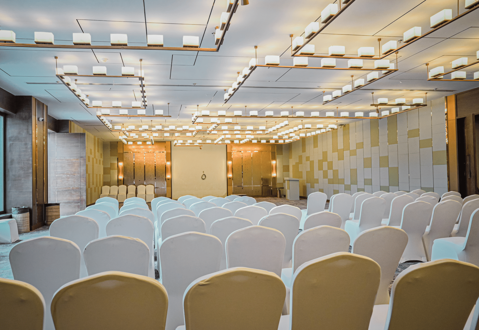 A close-up view of the front rows of chairs in an event space, with a stage and backdrop visible in the distance.