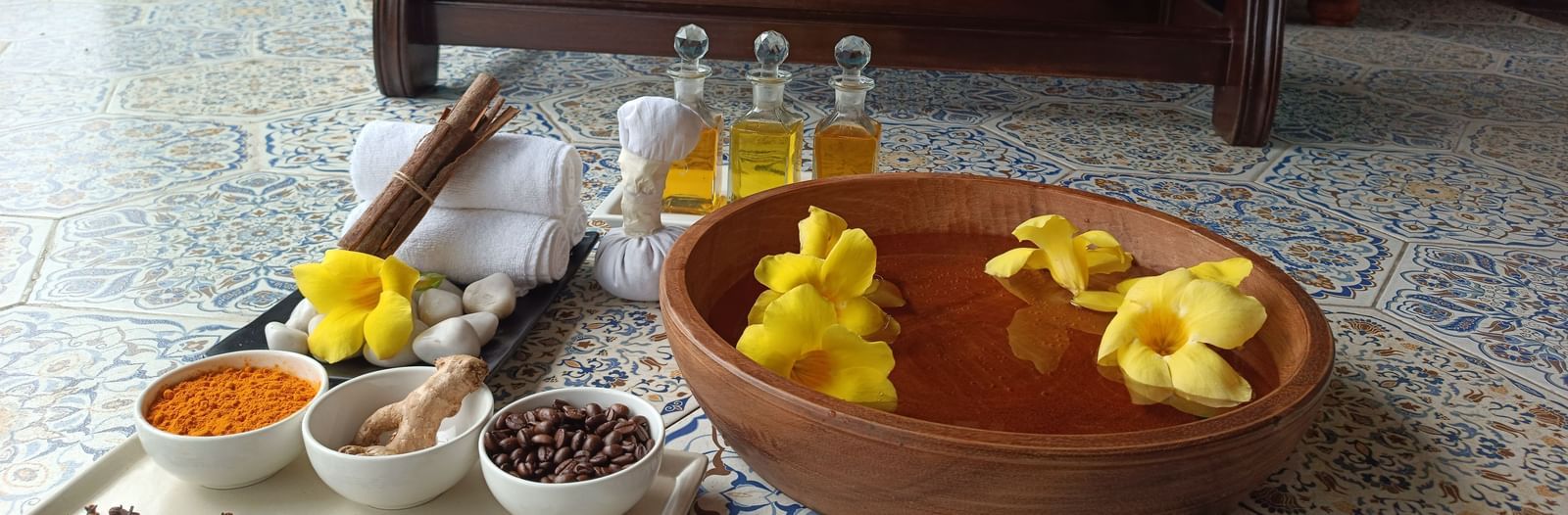 A detailed shot of a table at Polo Floatel Kolkata, with a large wooden bowl filled with water, yellow flowers, and yellow flowers as a decorative centerpiece.