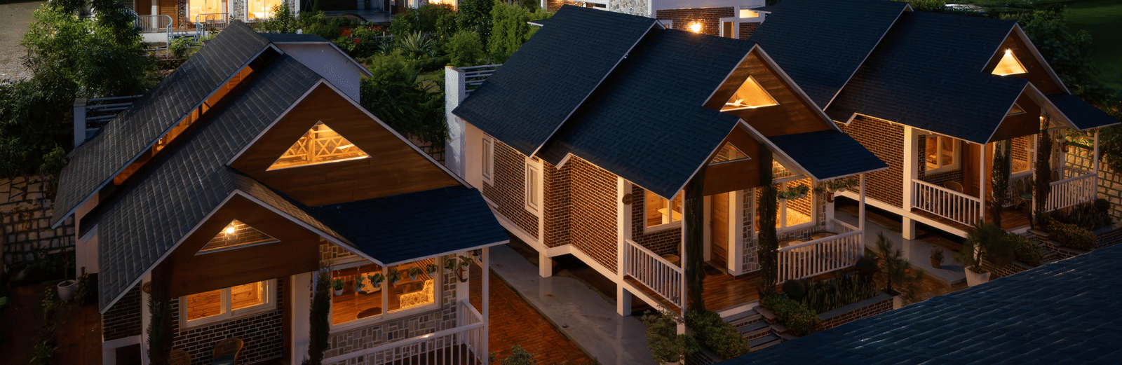 A row of wooden cottages lit up at night, surrounded by trees - Megha Resort & Villas, Dehradun