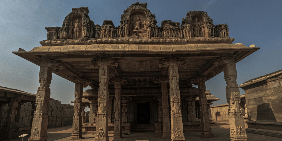 View looking into a historic temple hall with ornate stone pillars and a central altar.