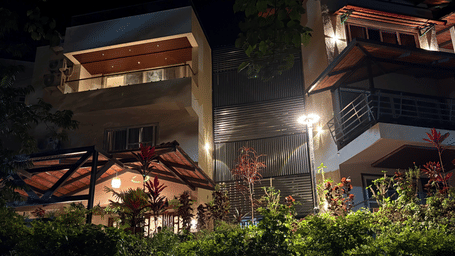 Warmly lit exterior of Lords Riverside Resort, Muduba - Shivamogga at night featuring modern balconies and green landscaping.