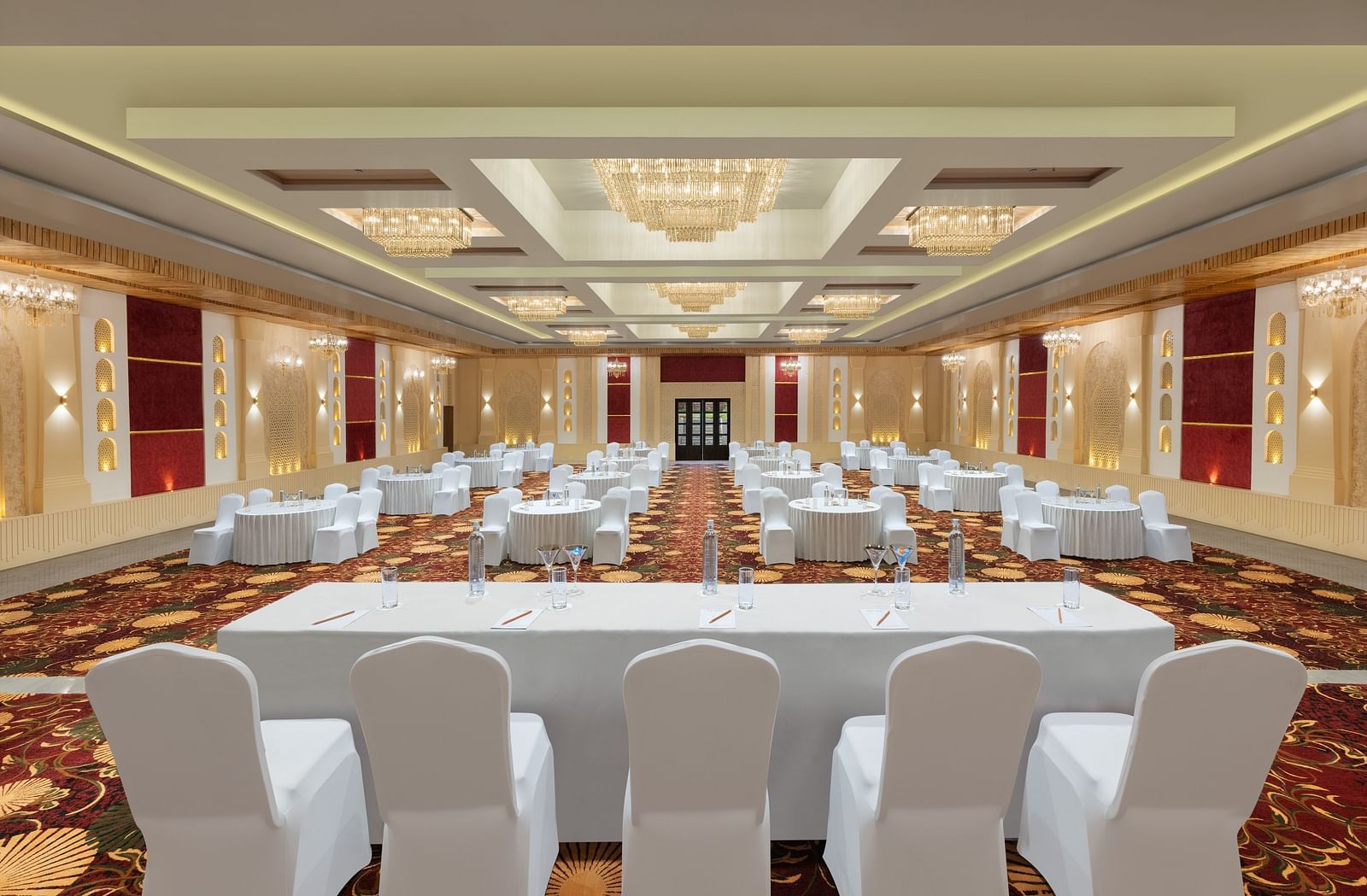Grand Ballroom banquet with chair setting facing towards the stage with a group of chairs placed in front of a single table at A dining setting of Blue Salt and Coffee at Essentia Luxury Resort & Spa, Udaipur.. 