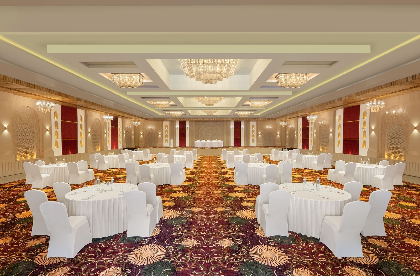Grand Ballroom banquet setting with white chairs and tables facing the stage at Essentia Luxury Resort & Spa, Udaipur.