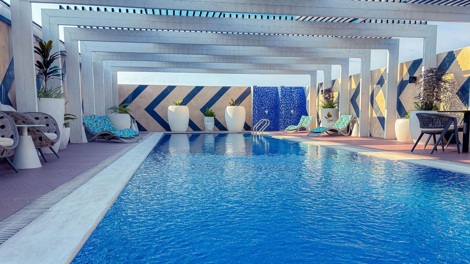 Swimming Pool at KertelSuites, featuring crystal-clear water under the open rooftop sky, with lounge chairs