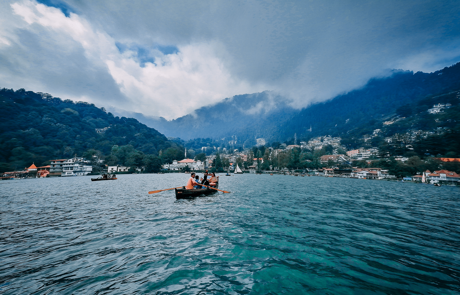 A photo of a lake with a boat on it and mountains in the background.