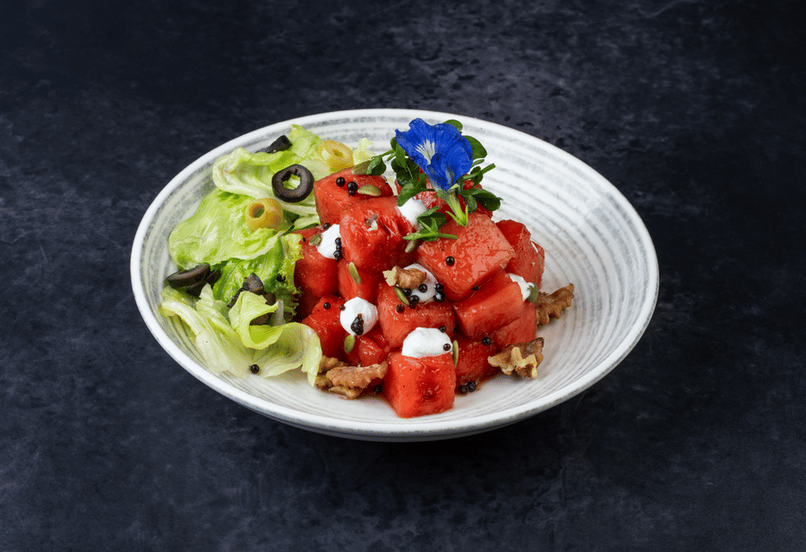 Watermellon Feta Breeze served with lettuce, olives, and garnished with a flower at The Wild Fork restaurant in La Marvella, Bengaluru.