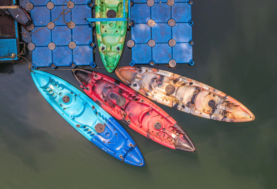 An overhead view of blue, red, and yellow kayaks on a floating dock.