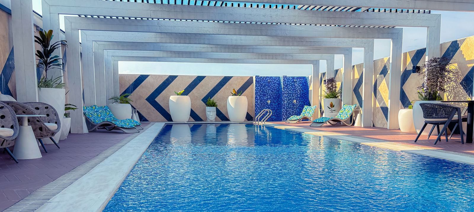 Swimming Pool at KertelSuites, featuring crystal-clear water under the open rooftop sky, with lounge chairs