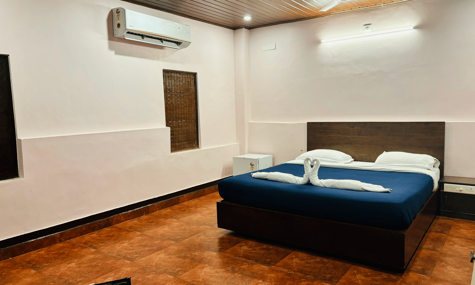 Spacious bedroom with queen bed, ceiling fan, and air-conditioning at Paradise Lagoon Resort, Udupi.