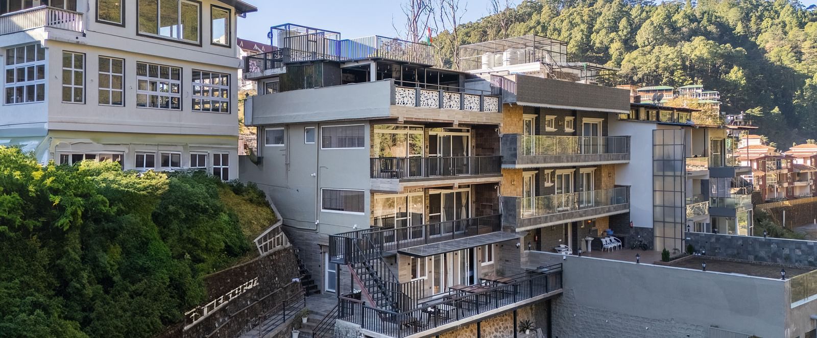 Exterior view of the hotel building with surrounding greenery and hillside landscape in the background.