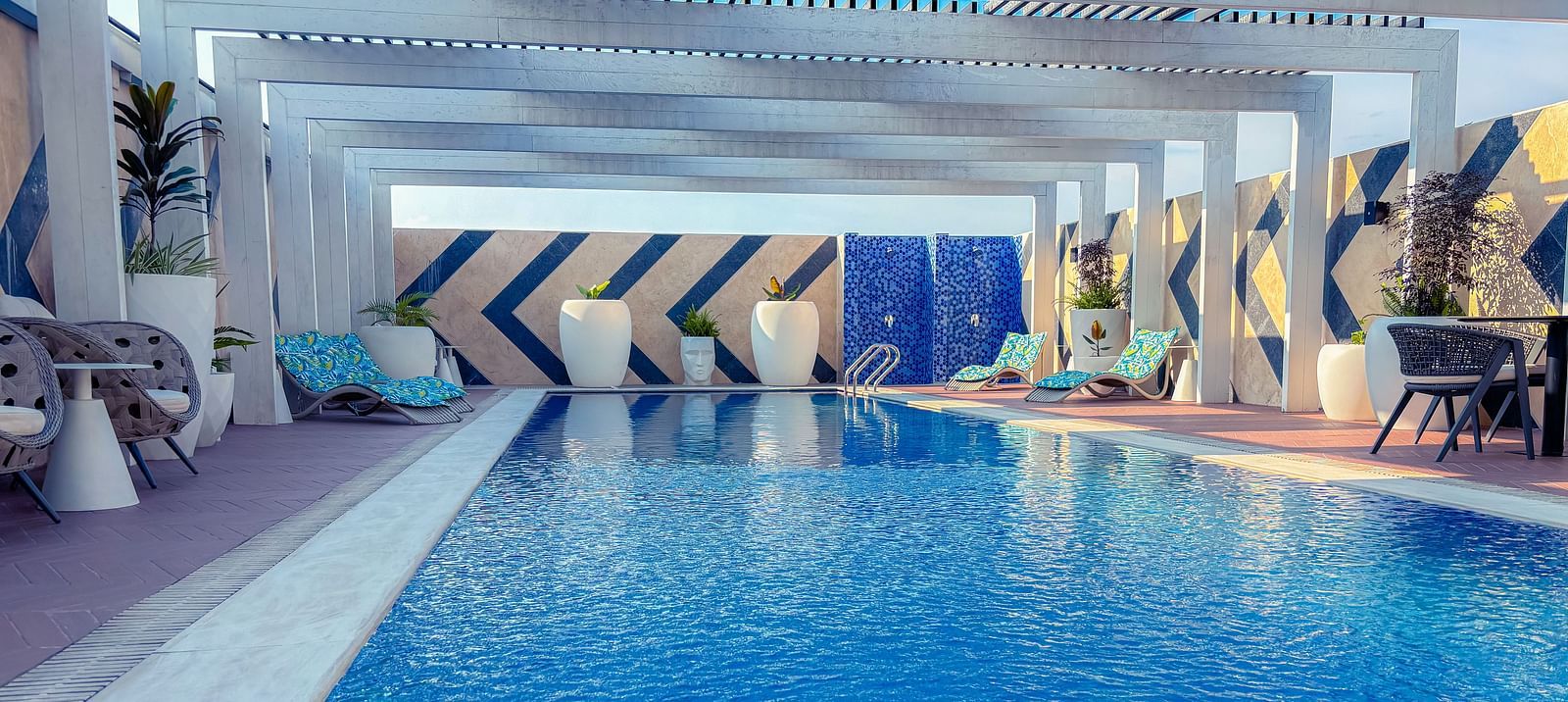Swimming Pool at KertelSuites, featuring crystal-clear water under the open rooftop sky, with lounge chairs