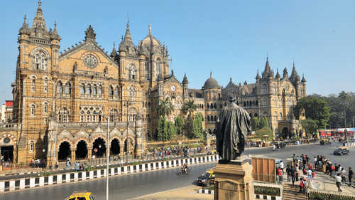A building with towers, roads, and vehicles in front.