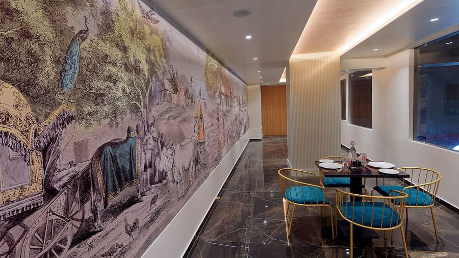 Image of seating area with chairs and tables and mural on the wall at Ankit Hotel, Jabalpur